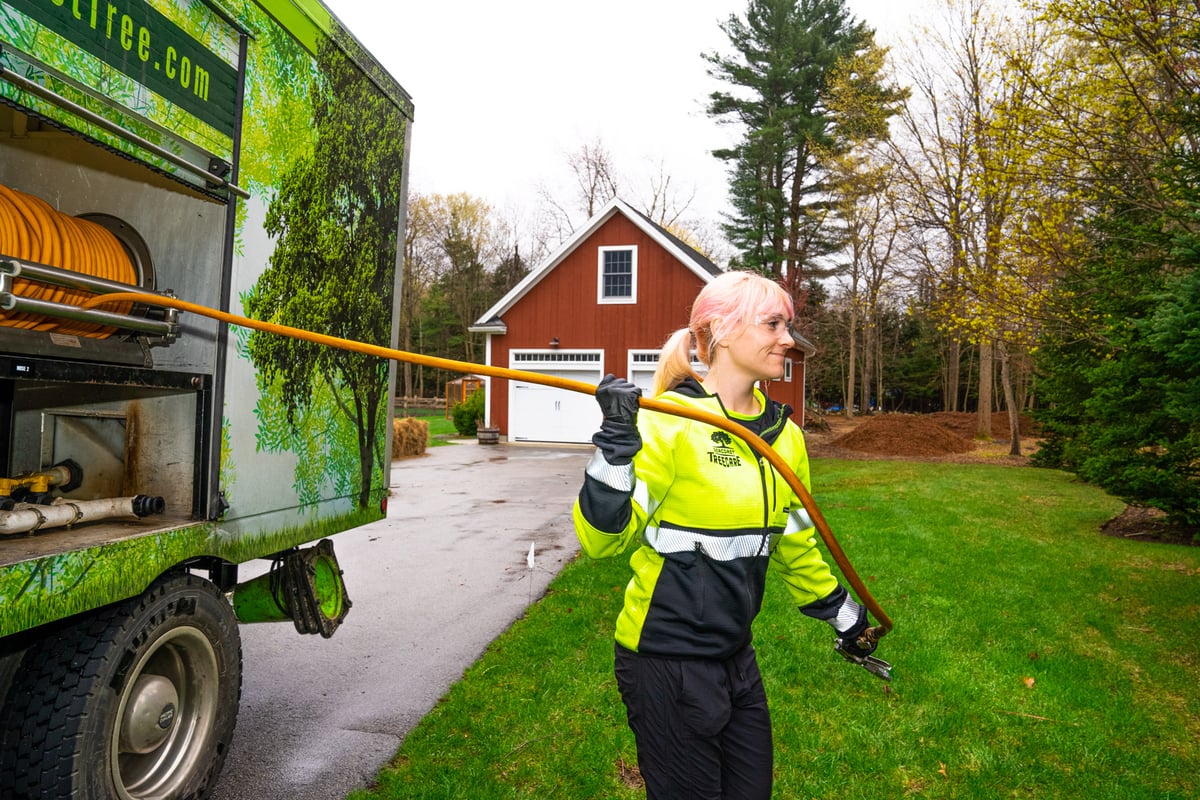 plant health care technician pulls hose out of truck for fertilization